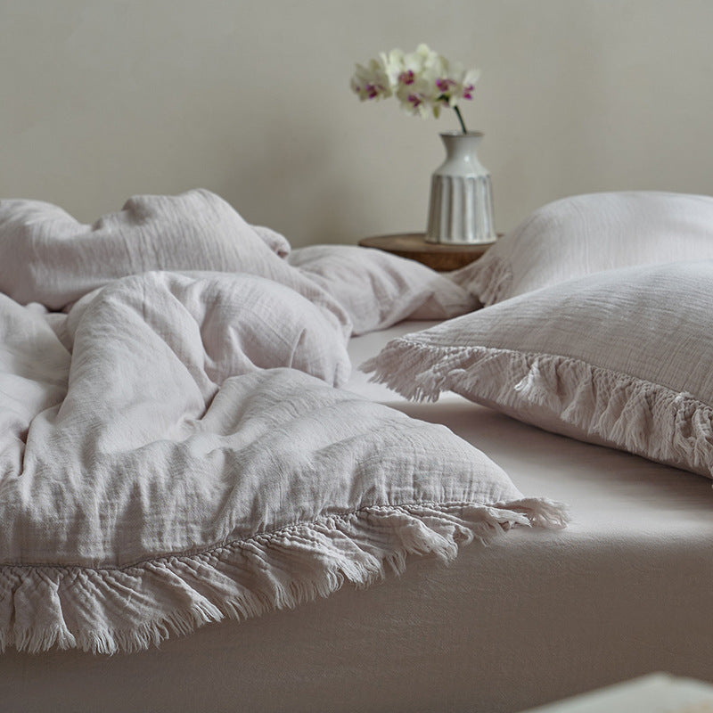 A close-up of Lilac cotton gauze duvet cover set, highlighting the soft texture and the fringe detail on the pillows and duvet.