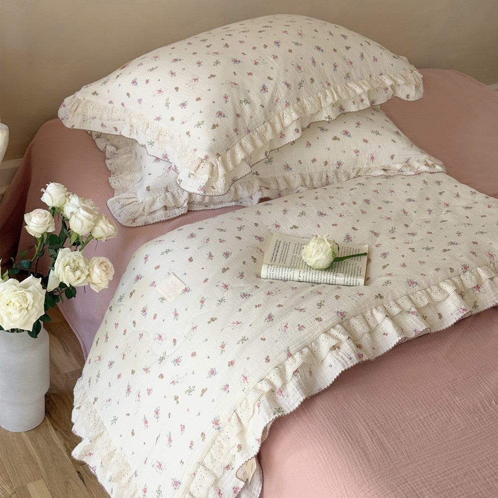 Floral cotton comforter with ruffled edges styled on pink floral bed