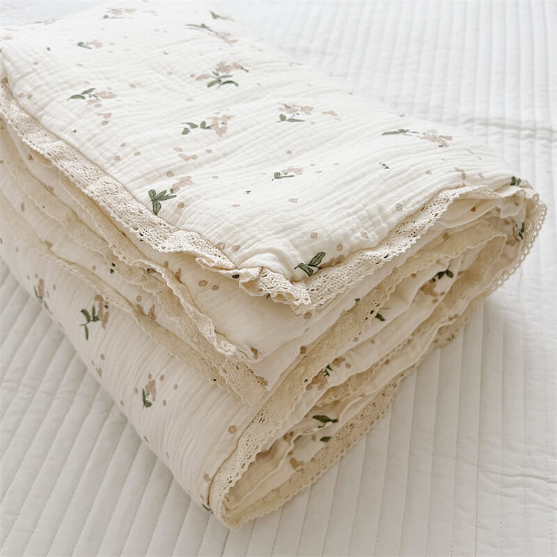 Folded floral cotton muslin comforter with ruffled lace edges