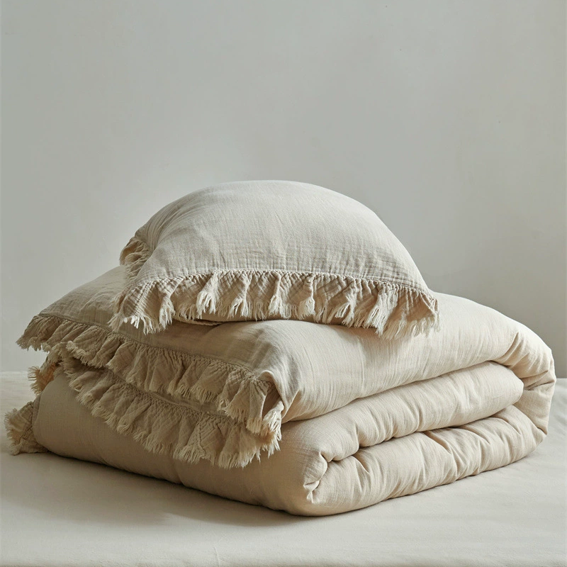 A folded khaki cotton gauze duvet cover and a matching pillow with fringe, neatly stacked and ready for use.