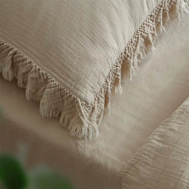 An extreme close-up of the khaki pillow from the bedding set, emphasizing the unique ruffled and fringed detail at the corner.
