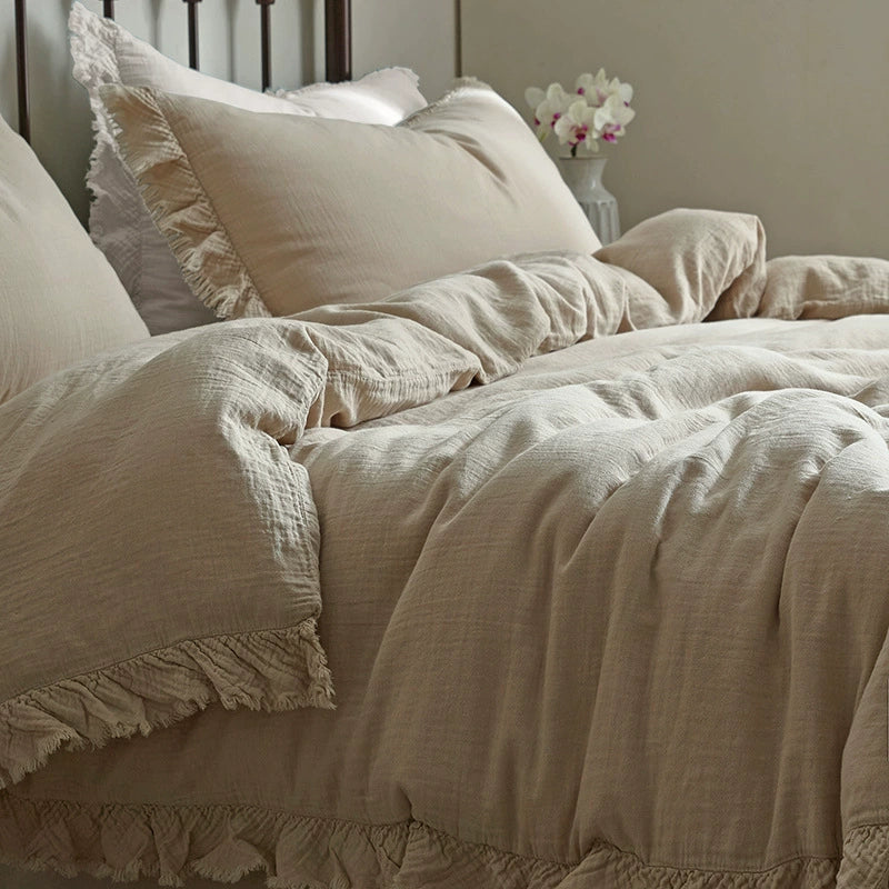 A stylish shot of a khaki fringe cotton gauze bedding set on a bed with a dark metal headboard, showcasing the product in a cozy bedroom setting