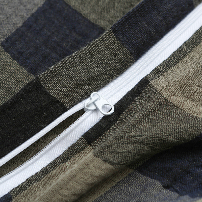 Macro shot of the white zipper on the army green and navy plaid fabric, showing fine fabric texture and zipper detail.