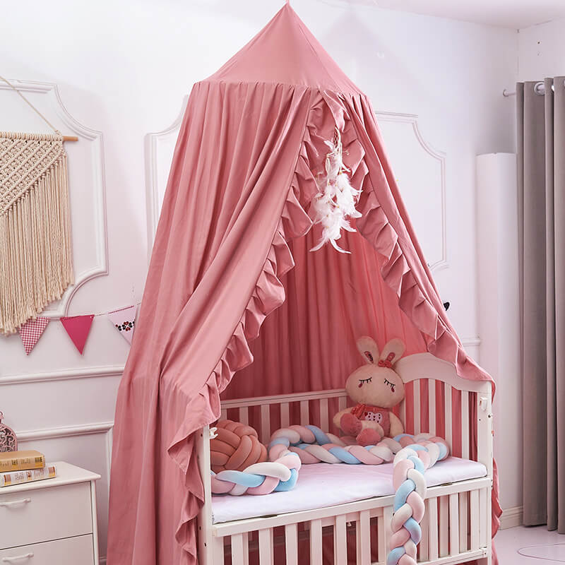 Ruffled bed canopy for a crib in a girl's room, in a soft pink color.