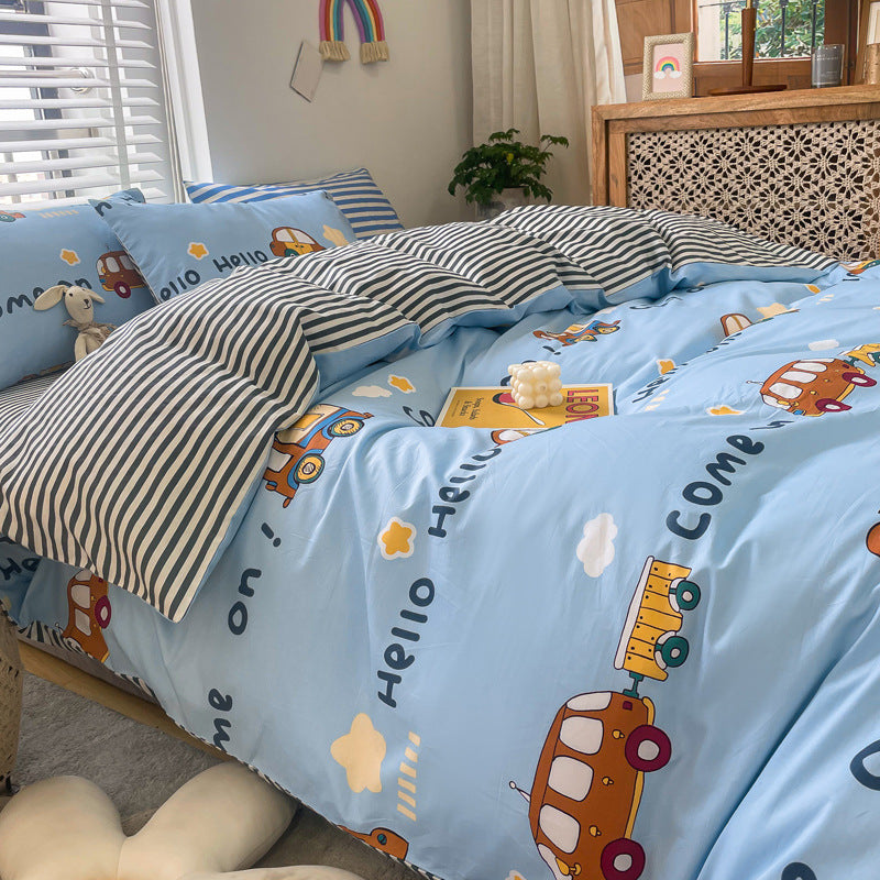 A close-up of a kids' bedding set with a car print. The duvet cover is light blue with a pattern of cartoon cars and text, accessorized with striped and solid-colored pillows