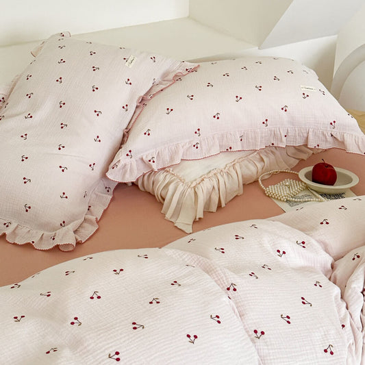 An overhead view of the cherry print ruffled duvet cover set on a bed, showing the duvet and two matching pillow shams.