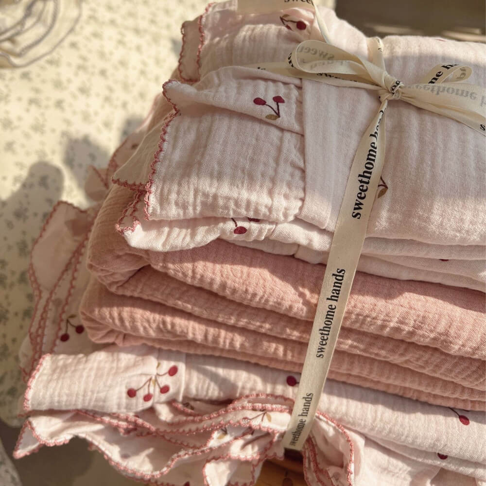 A close-up shot of the folded pink cherry print ruffled duvet cover and sheet, tied with a ribbon.
