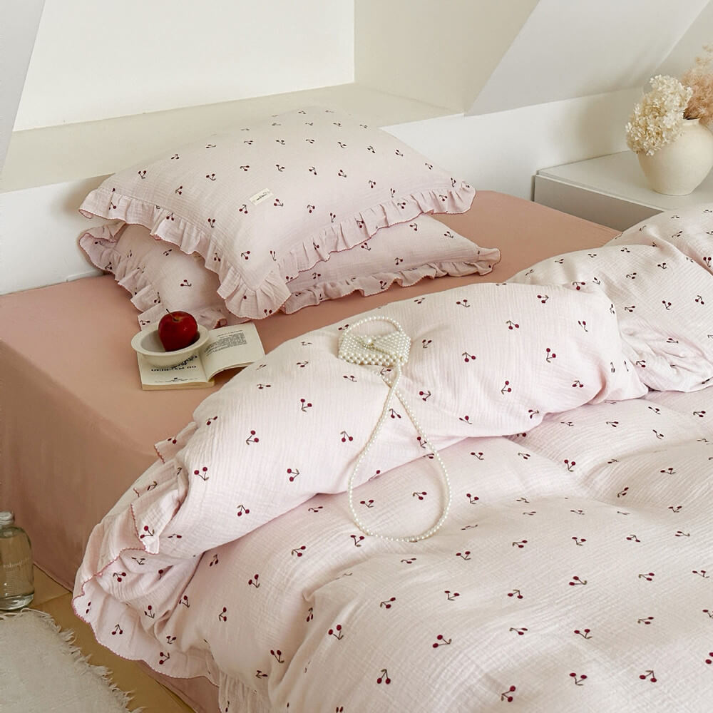 A Twin-size bed styled with the cherry print cotton muslin duvet cover set, showcasing the pillows with ruffled edges.