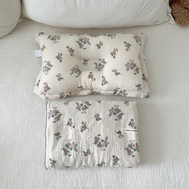 A flat-lay photo of the Vintage Floral muslin blanket and pillow set, showing the full design with its delicate flower bouquets and matching pillow.
