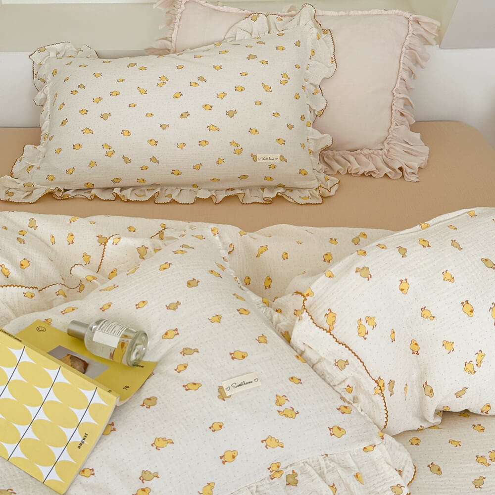 A close-up shot of a cute duckling print duvet cover set with ruffled pillowcase and matching flat sheet