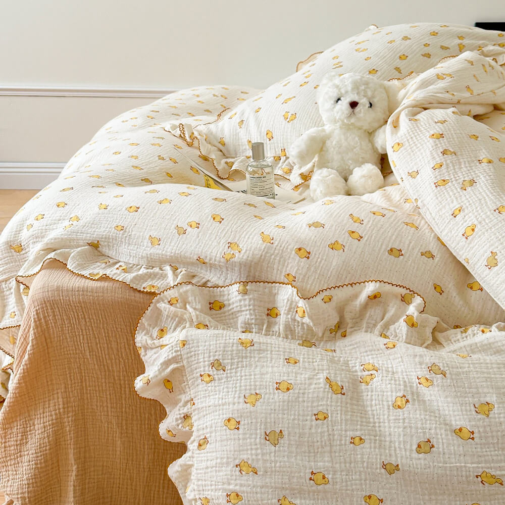 a ruffled white cotton muslin duvet cover set featuring a subtle yellow duckling print