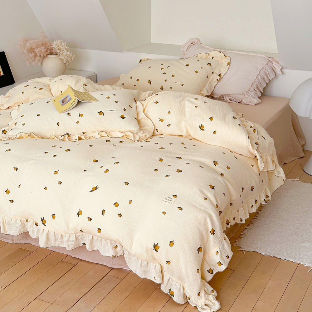 A neatly made bed with the Zesty Lemon cotton muslin duvet cover set, featuring a ruffled pillow and a larger accent pillow