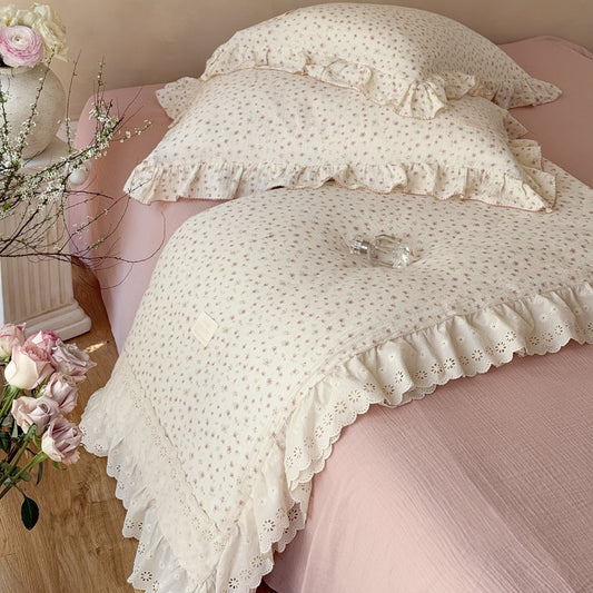 Pink floral cotton comforter with ruffled trim on bed