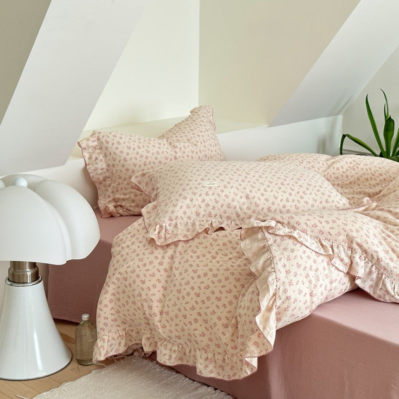 Ruffled pillowcases and floral gauze comforter on soft pink bed