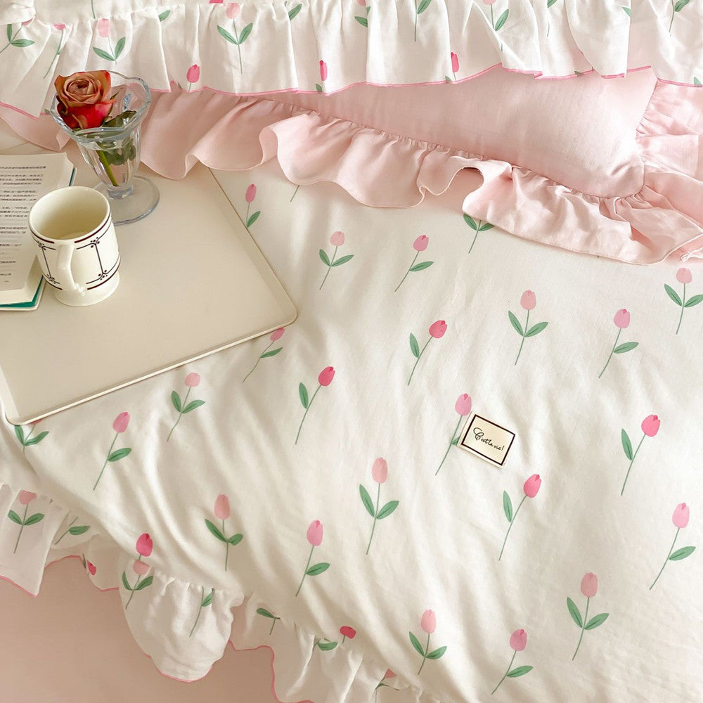 A close-up view of the pink cherry print ruffled duvet cover and matching shams, styled on a bed.