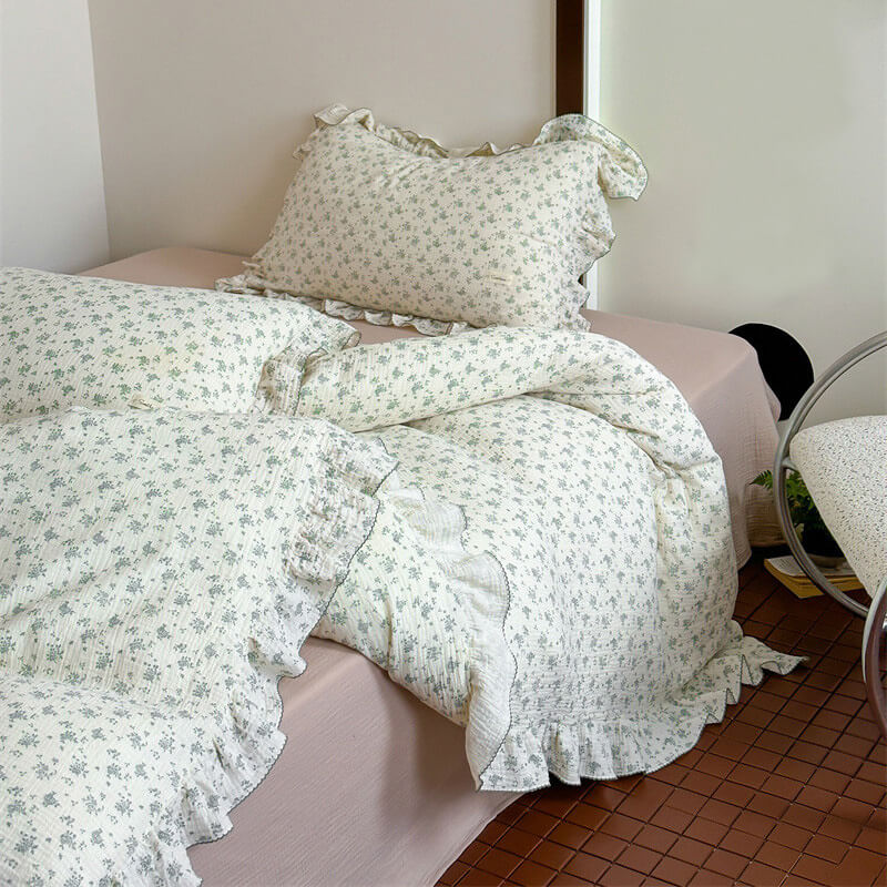 Green floral ruffle bedding set styled on a queen bed with mauve flat sheet
