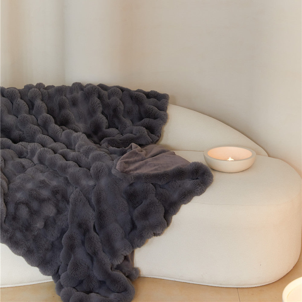 Luxury Charcoal reversible faux rabbit fur blanket on a white sofa with a candle.