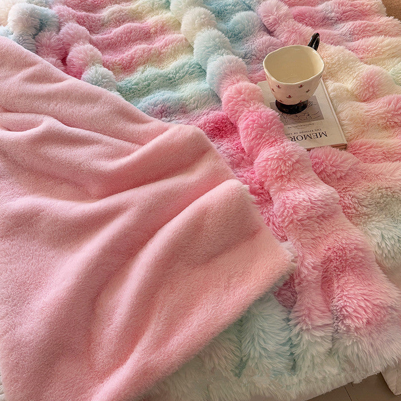 Reversible faux rabbit fur blanket, showing a rainbow pastel side and a plain pink fluffy side