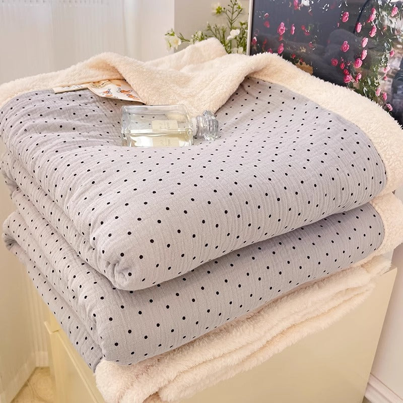 A multi-color polka dot print soft fleece kids blanket, ideal for winter, folded on a white dresser.