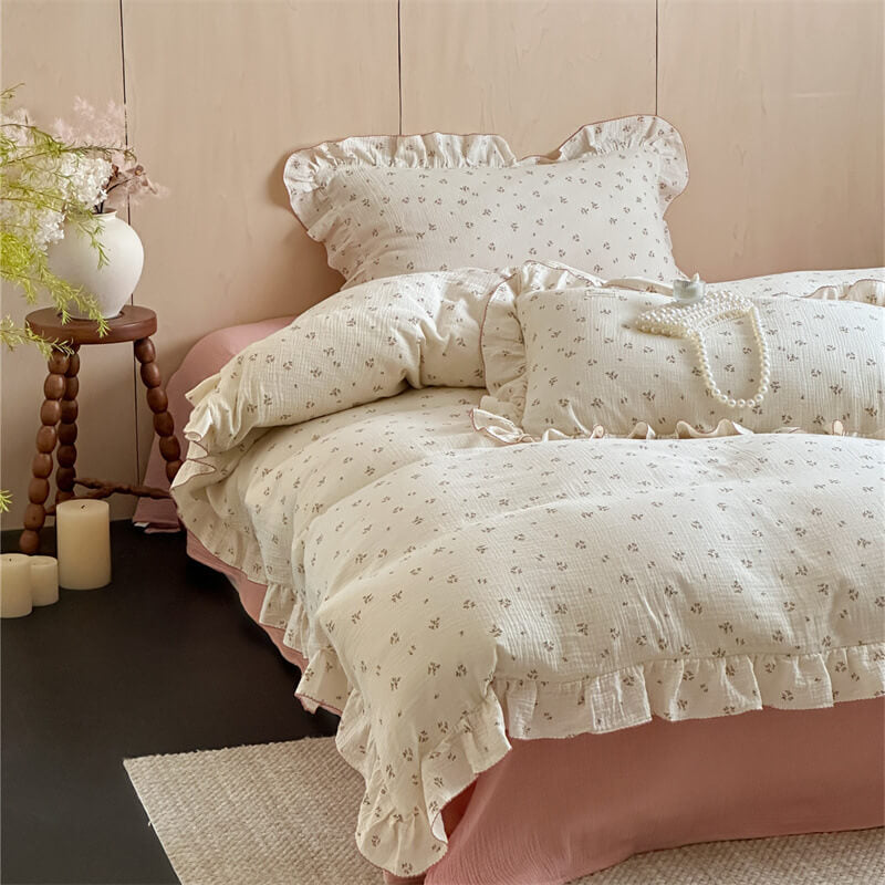 Two pillows with a small floral print and ruffles, resting on a pink bedsheet, highlighting the soft cotton muslin texture.