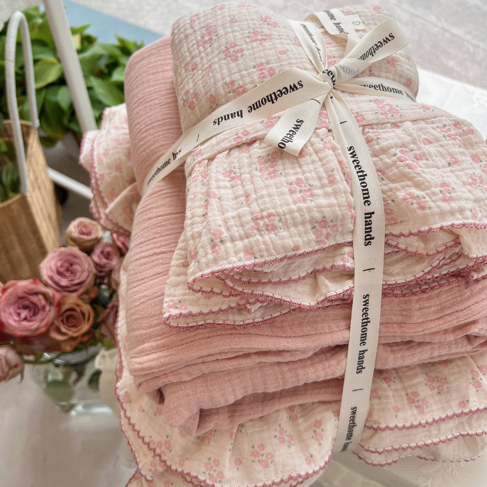 Folded muslin duvet cover set with ruffles and carmine floral pattern, tied with ribbon