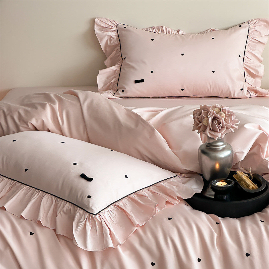 Soft pink cotton bedding with ruffle trim and heart embroidery