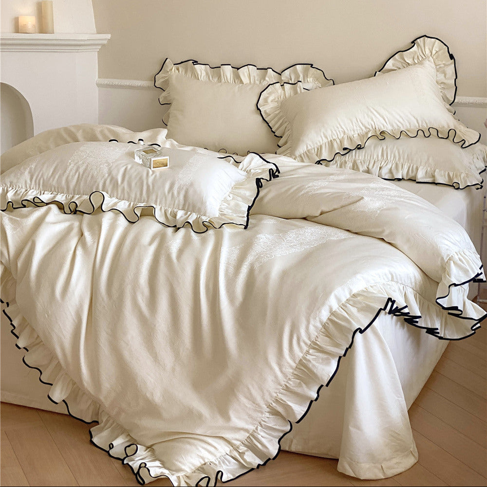 Ivory satin ruffle bedding set with black trim on bed