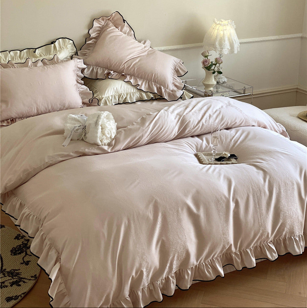 Blush pink and ivory satin bedding layered with ruffled pillows and duvet