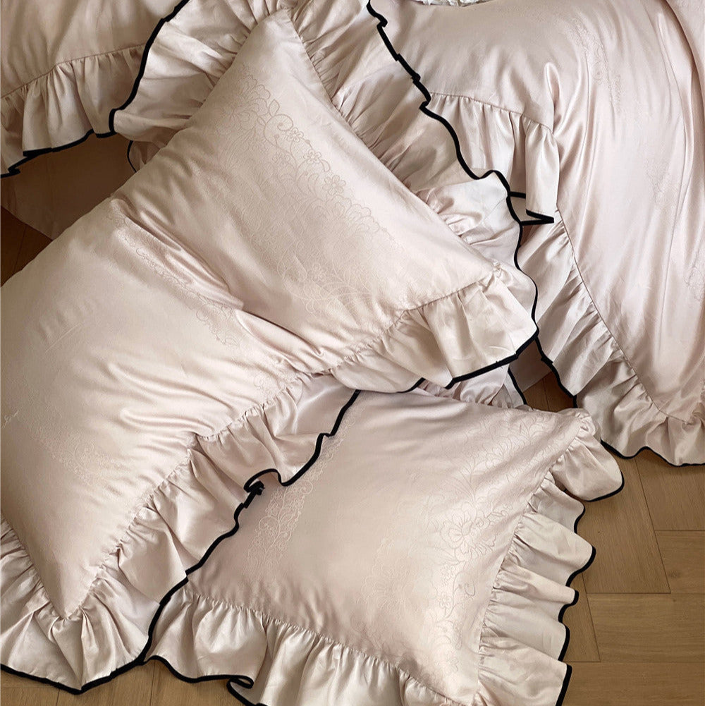Blush pink ruffle bedding set with matching pillows in romantic bedroom setup