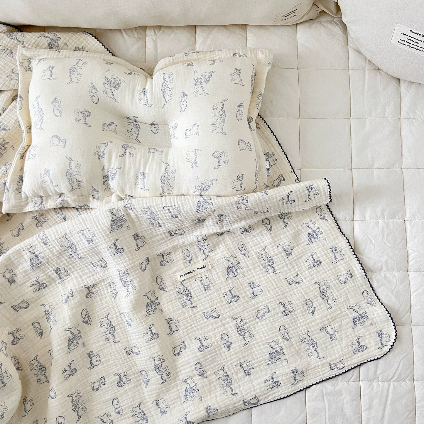 Blue kitty print muslin blanket and matching pillow set on a baby bed