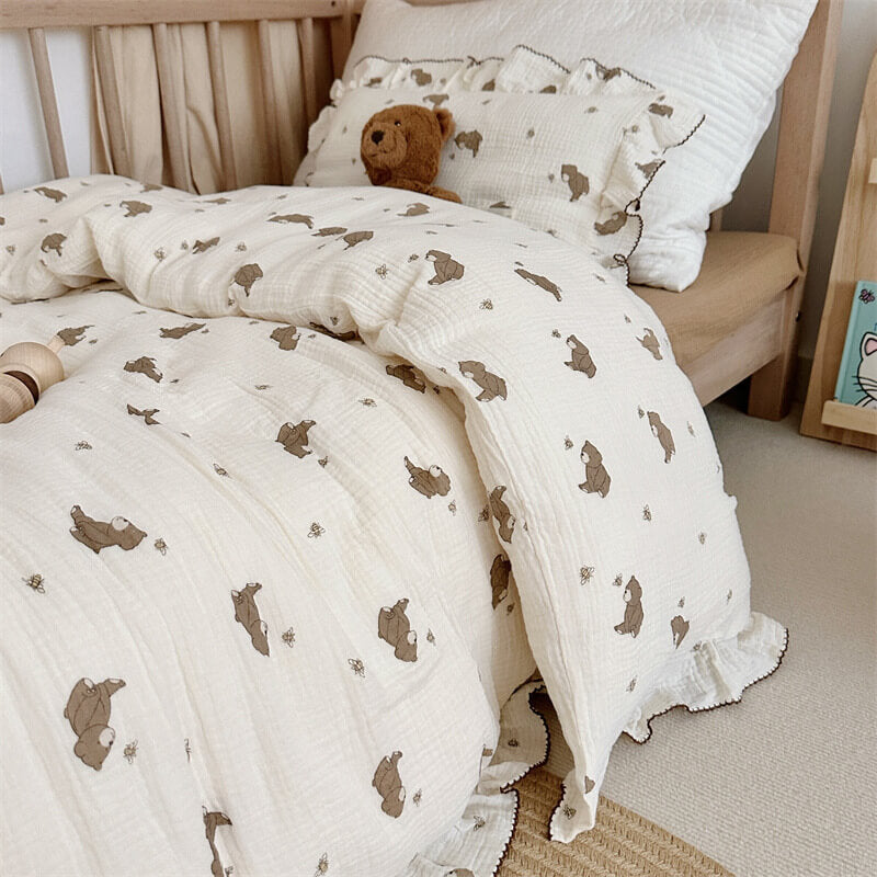 Bear print cotton muslin bedding set with ruffled edges styled on a wooden toddler bed