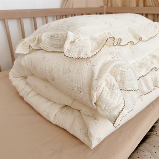Cream cotton muslin lamb ruffle duvet cover set  folded on a crib bed