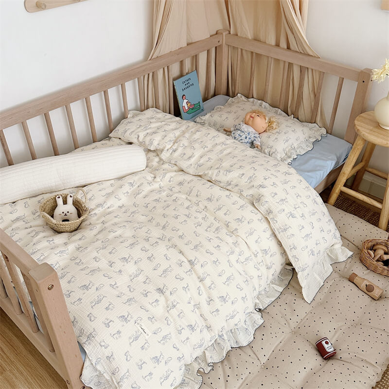 Ruffled cotton muslin kitty duvet cover set with blue cat print and plush bear on a kids bed