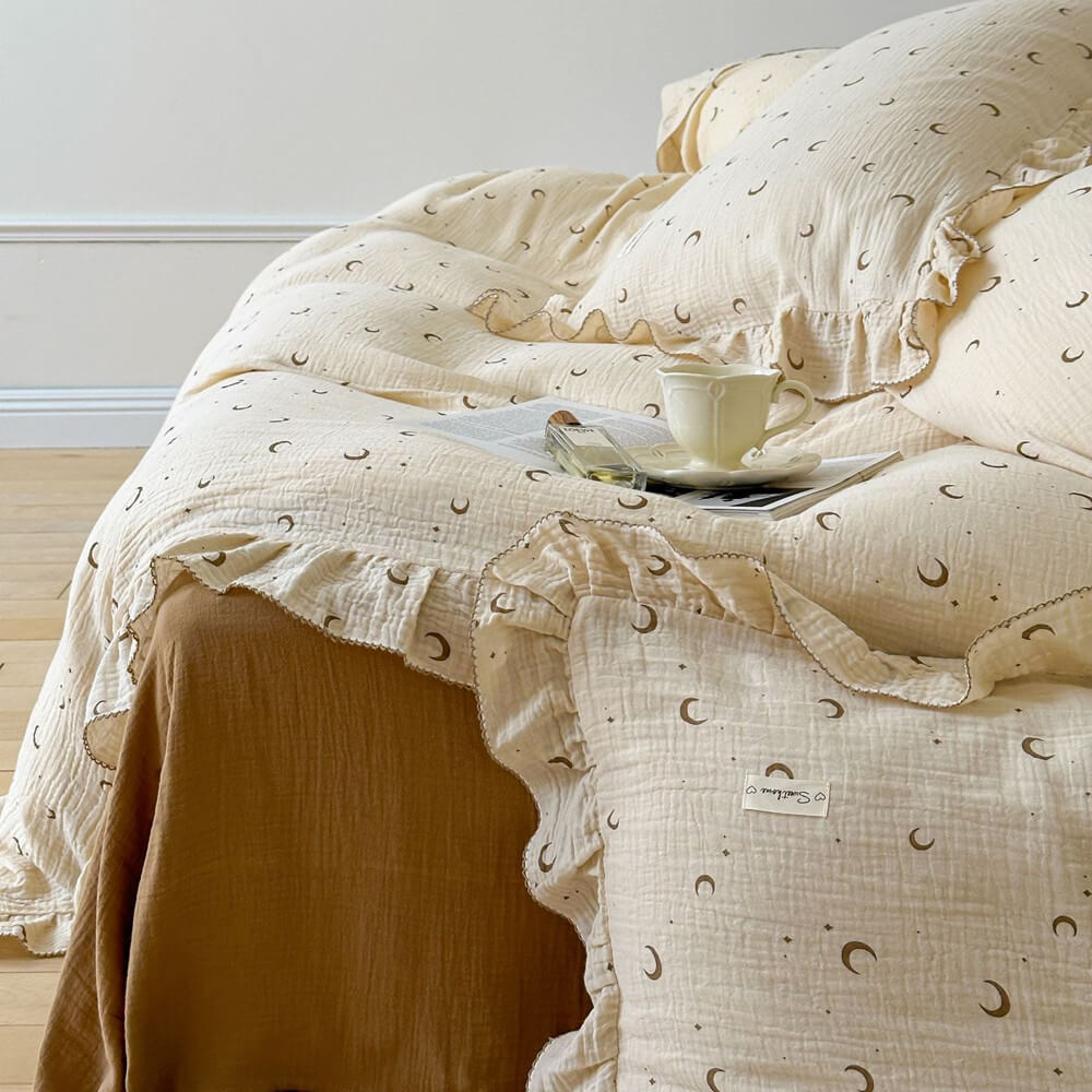 A bed dressed with a moon and star print cotton muslin duvet cover and ruffled shams.