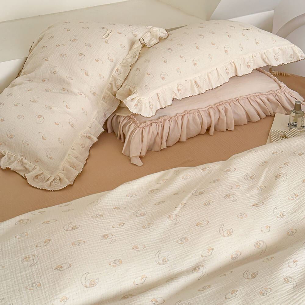 An overhead view of a twin bed with the lamb print cotton muslin duvet cover set, highlighting the ruffled edges.
