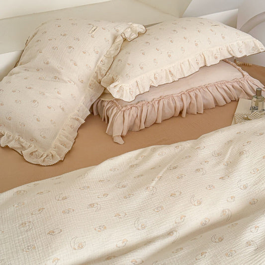 An overhead view of a twin bed with the lamb print cotton muslin duvet cover set, highlighting the ruffled edges.