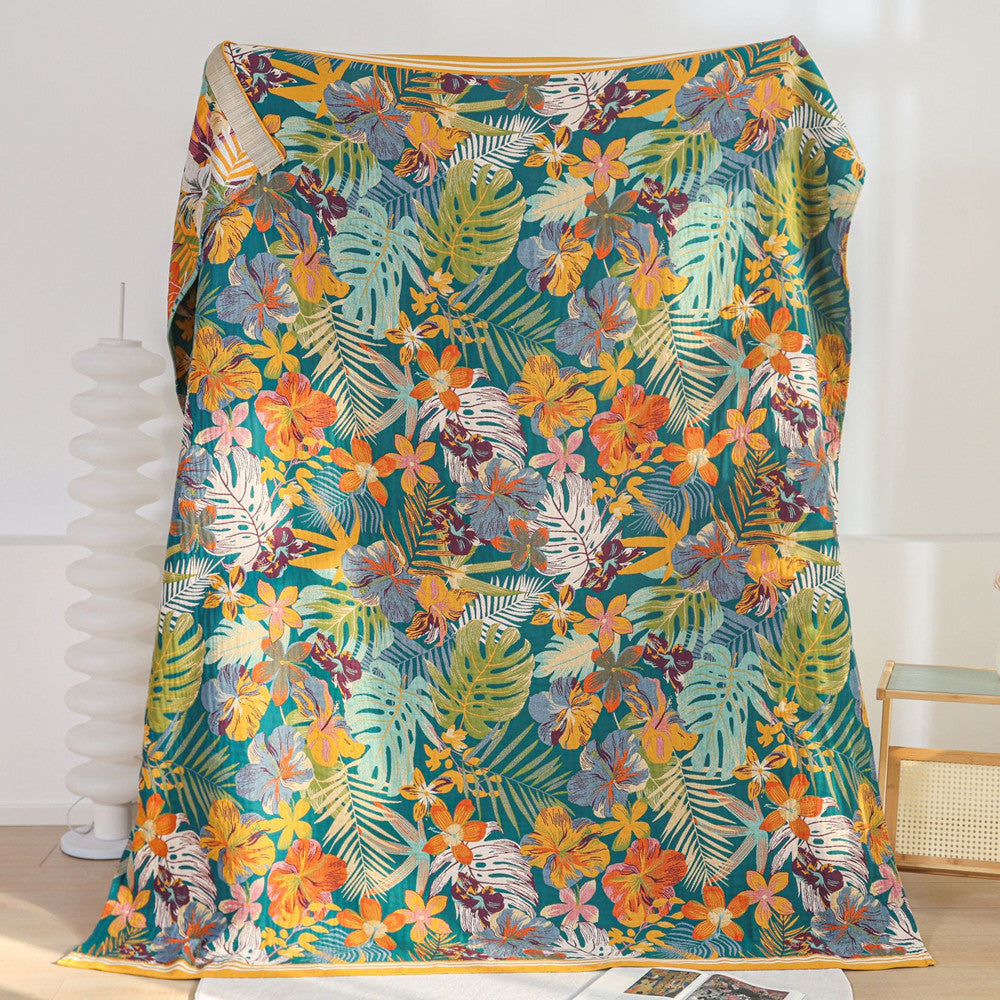 A full view of a tropical paradise jacquard blanket, held up to showcase its rich, detailed pattern of large flowers and lush green foliage.