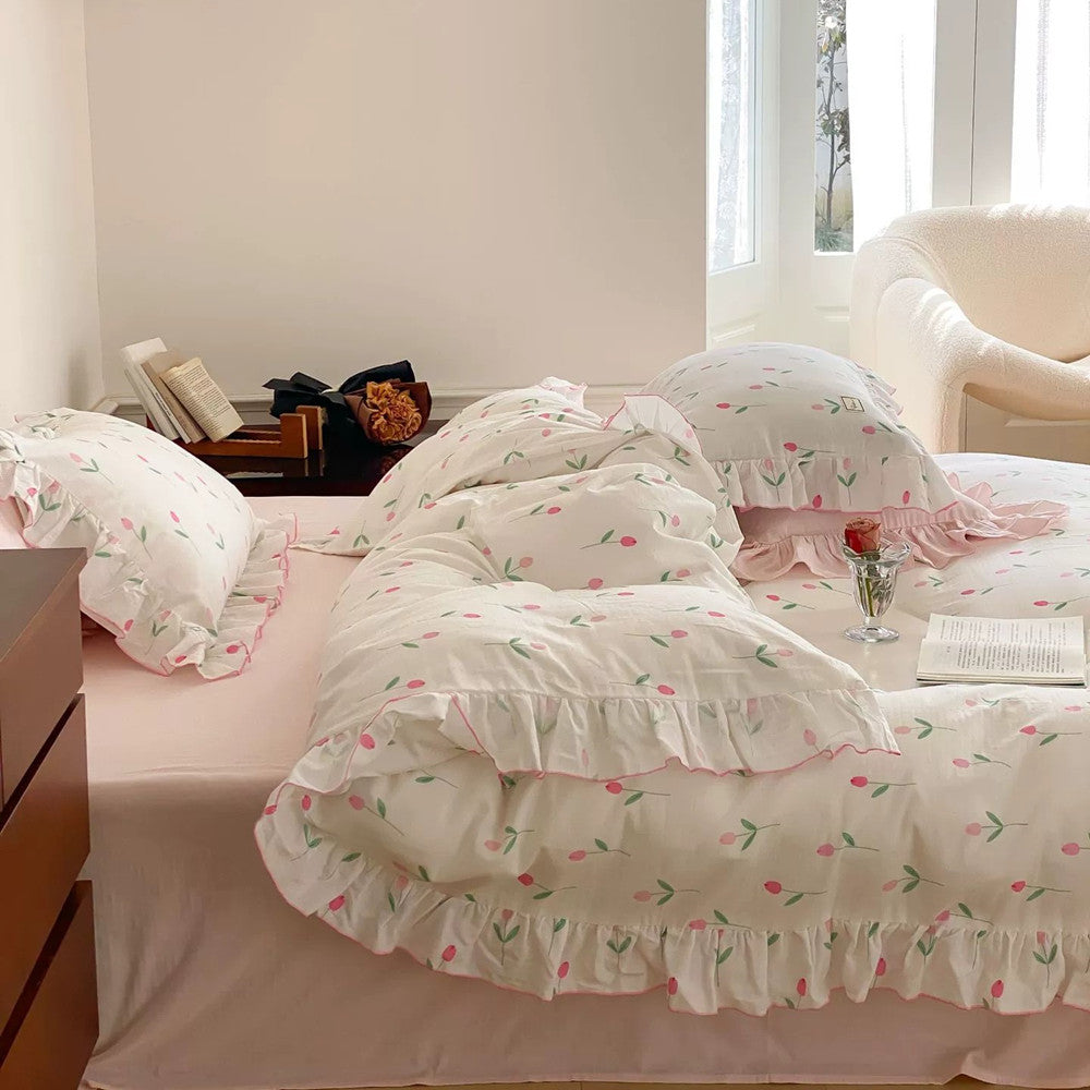 A close-up of a bed with the pink tulip print cotton muslin duvet cover, showing the ruffled trim