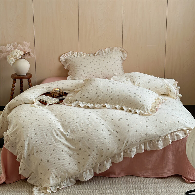 A full twin bed styled with a small floral ruffle duvet cover set, featuring a soft pink bed skirt and decorative pillows.