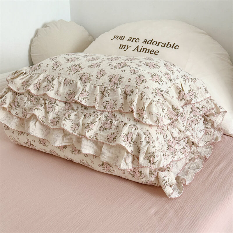 Folded ruffle bedding set with pink floral print and frilled trim on pink bed