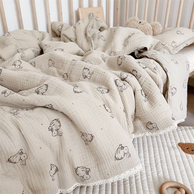 Lightweight bunny print cotton muslin comforter with lace trim spread over toddler bed