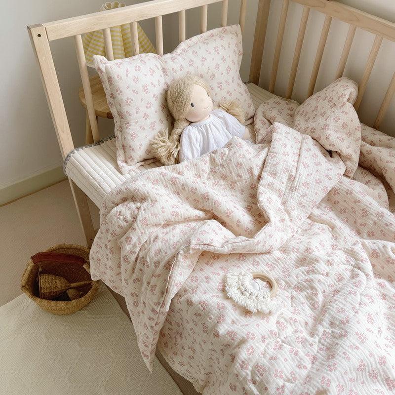 Floral muslin baby comforter styled in toddler crib