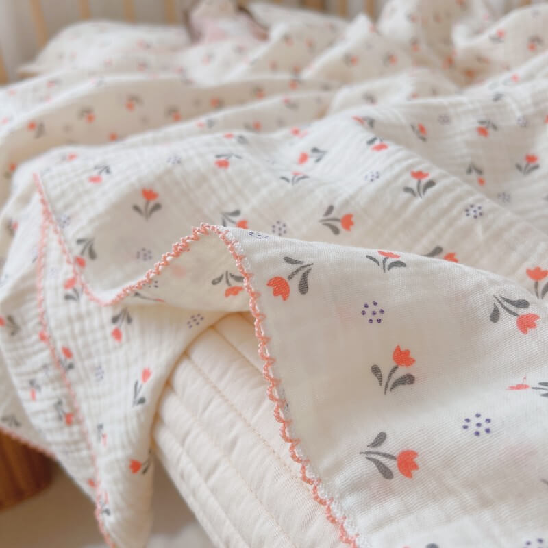 A detailed close-up of the tulip floral muslin blanket, highlighting its soft, multi-layered texture and decorative pink scalloped edge.
