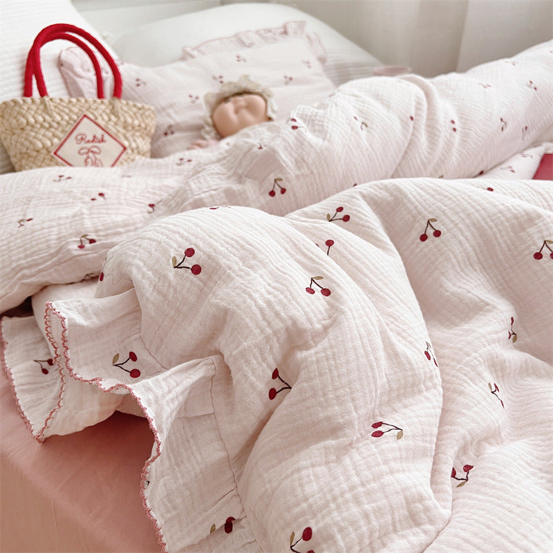 Close-up of cherry print ruffled pillowcase and cotton muslin bedding