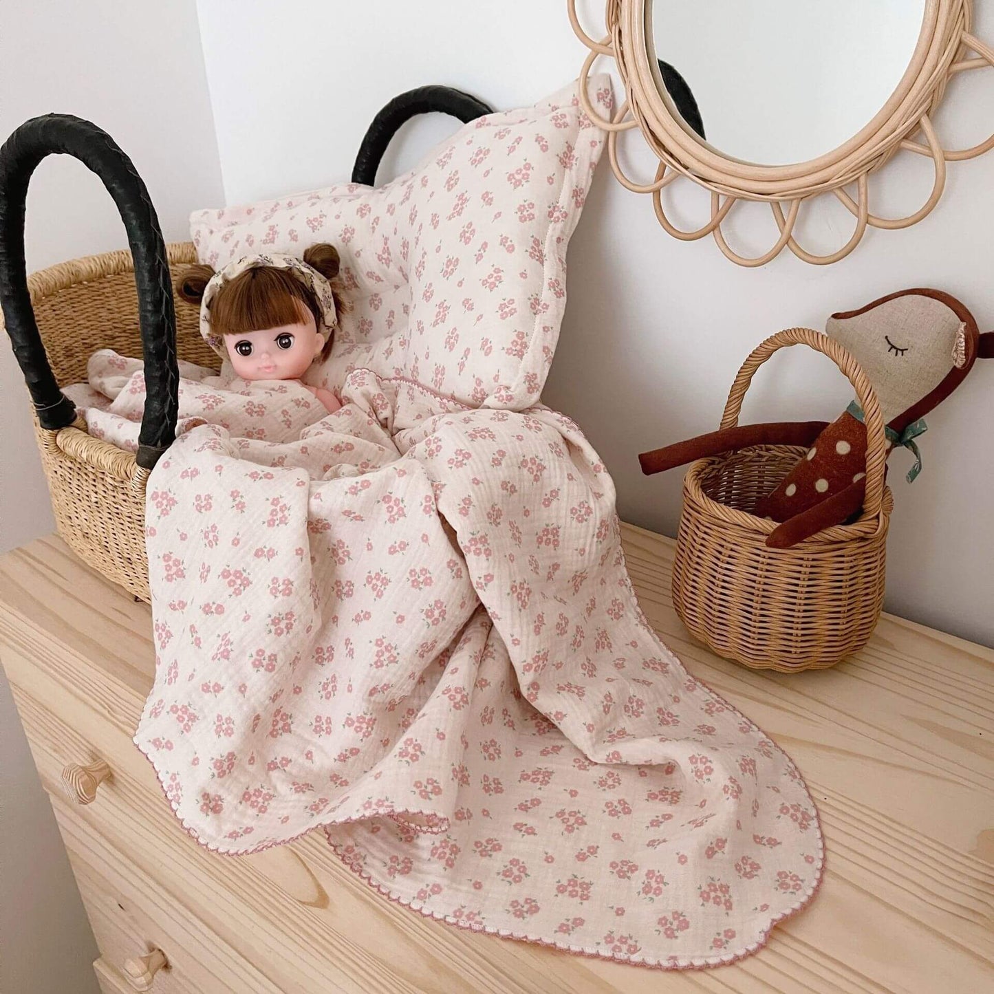 Vintage floral muslin baby blanket and pillow set with a doll in a woven bassinet.