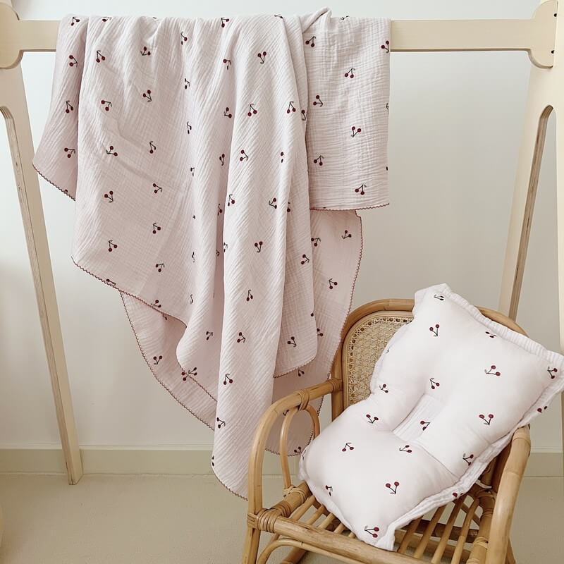 Full set of the Soft Cherry Blossom baby blanket and pillow hanging on a wooden rack.
