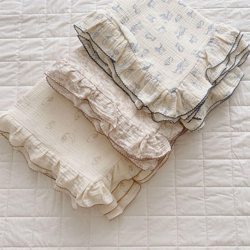 Group of animal print ruffle duvet cover sets—woodland, kitty, and lamb—stacked on white quilt