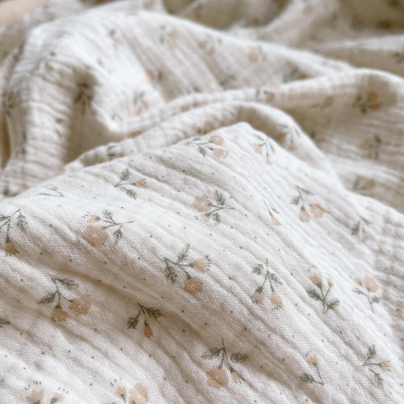 Close-up of a soft, textured muslin security blanket with a vintage floral pattern, showing the gentle crinkles of the fabric