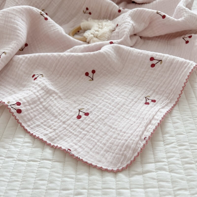 Soft cherry blossom newborn receiving blanket with delicate cherries and a frill trim.