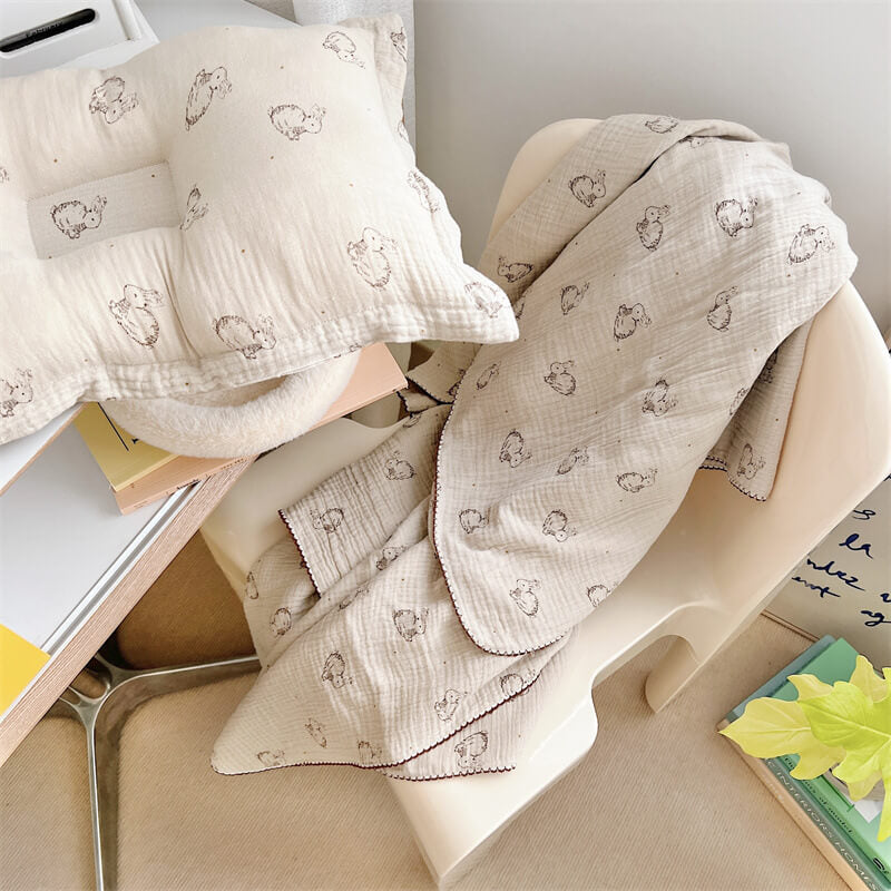 Bunny pattern baby blanket and matching pillow set draped over a modern chair.